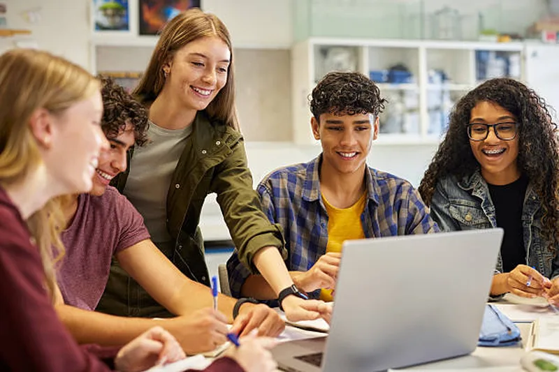 Students gathered around a laptop, working together